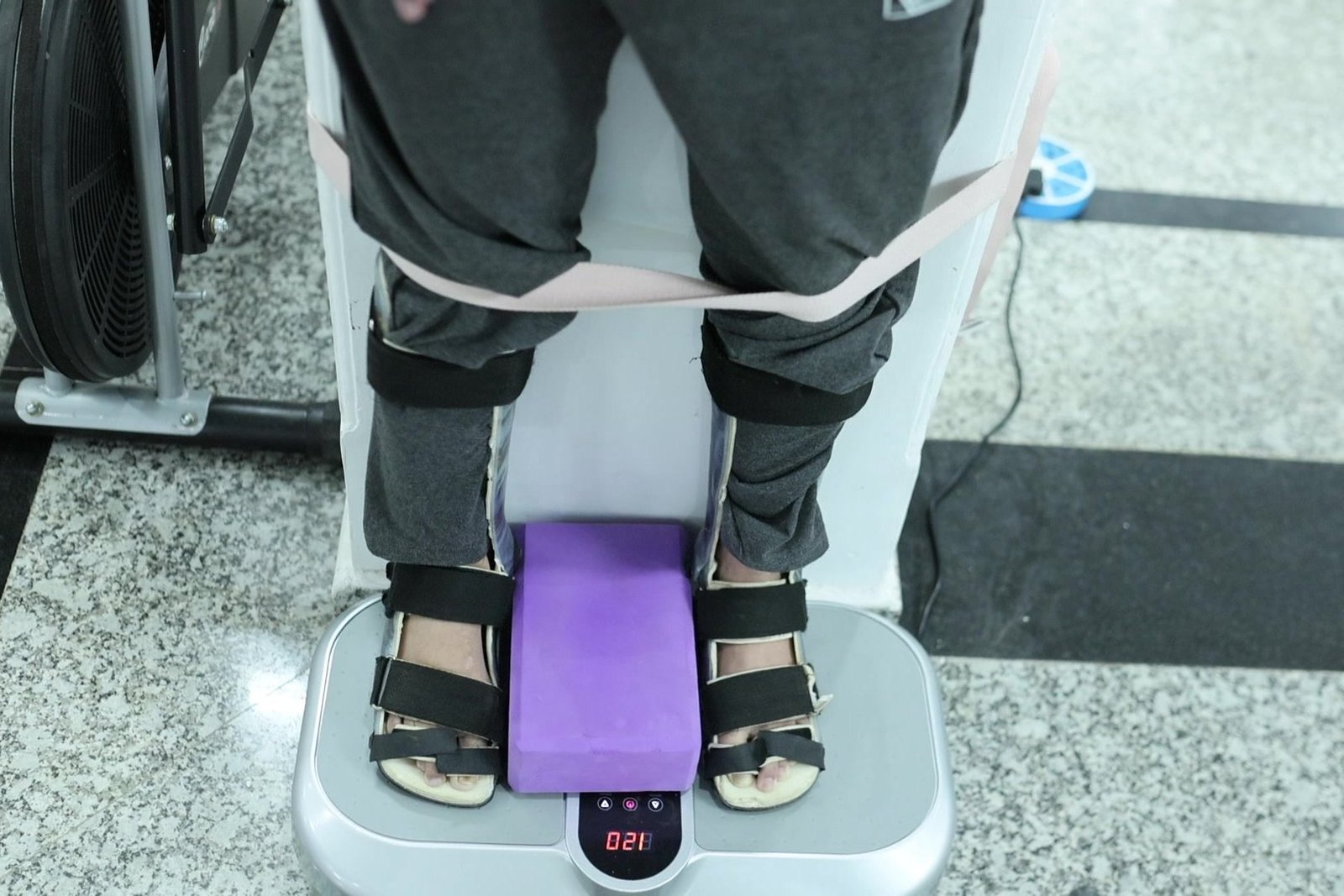 Balance and coordination training at Neuranta, Sector 39 Gurugram — a patient standing on a vibration platform in ankle-foot orthoses with a resistance band around the knees