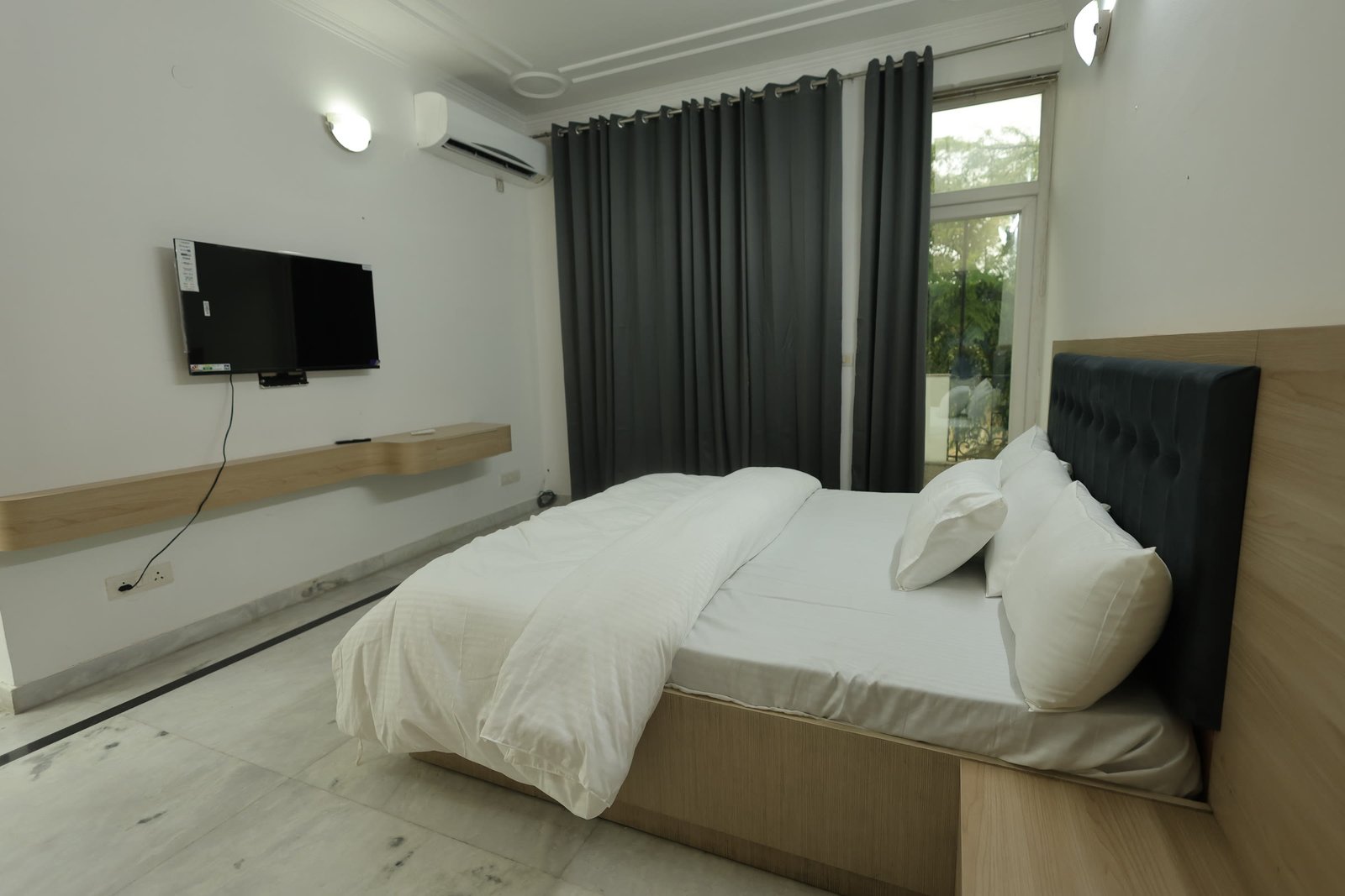 Inpatient suite bedroom at Neuranta, Sector 39 Gurugram, with full-height curtains and a balcony window