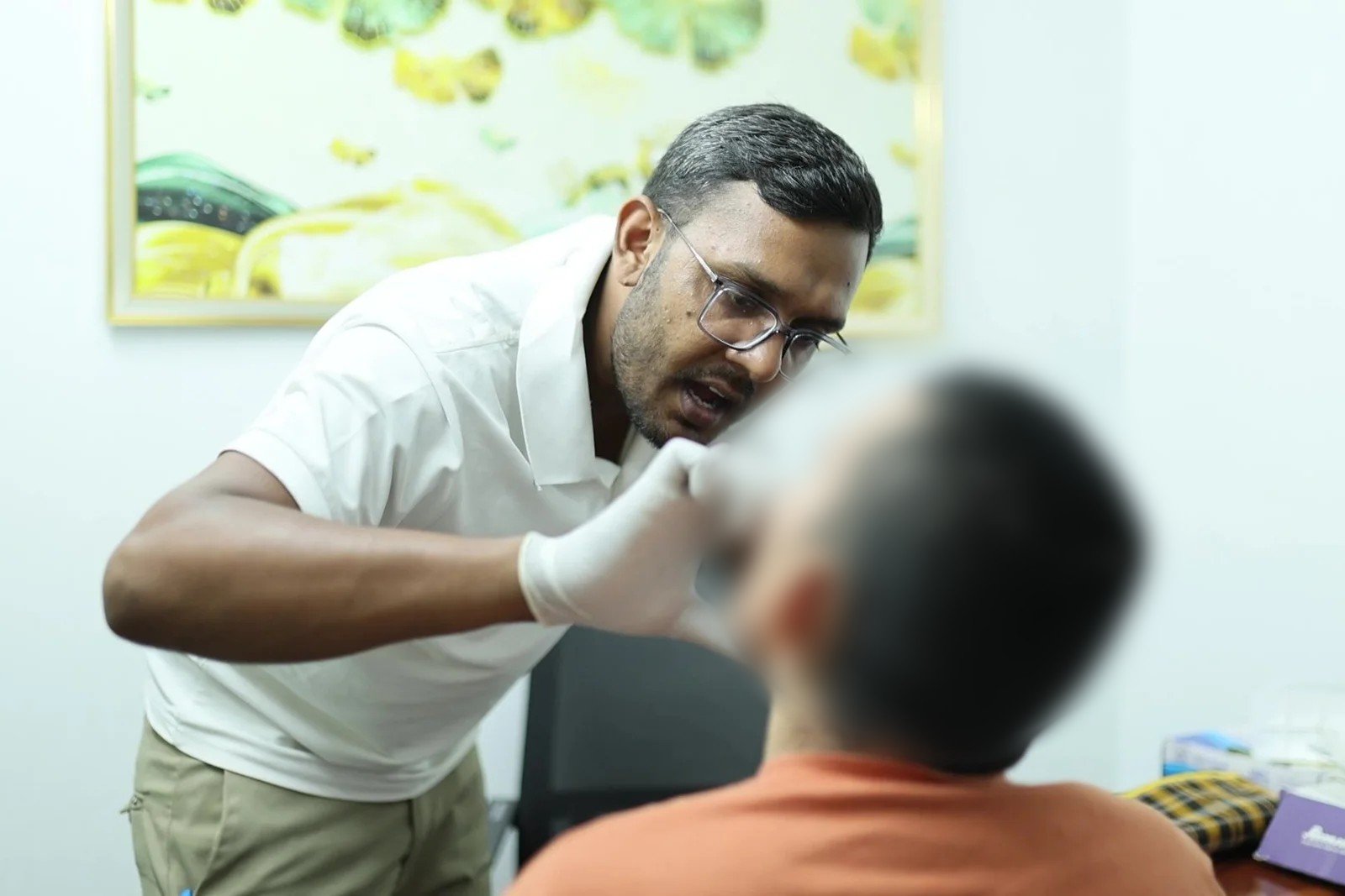 Speech therapy in Gurugram at Neuranta, Sector 39 — a speech therapist guiding gloved oral-motor exercises used in swallowing rehabilitation and speech recovery after stroke; the patient is seen from behind with the face blurred