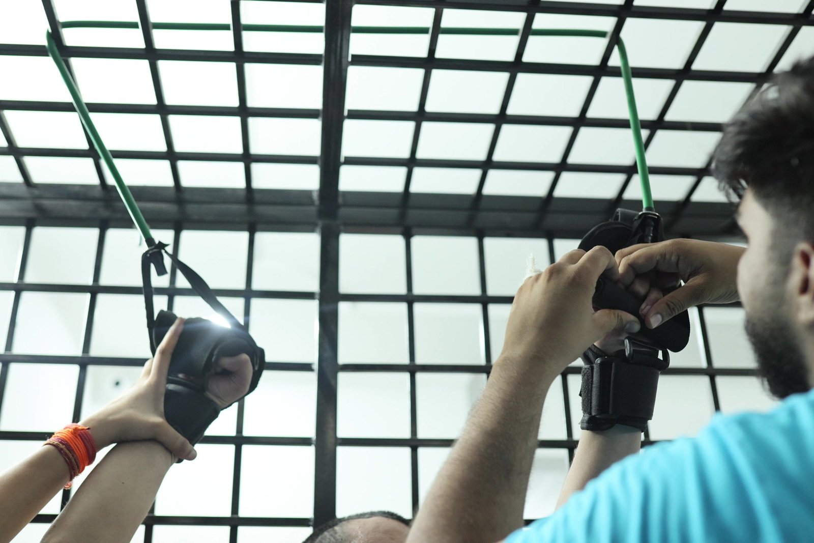 Upper-limb strengthening at Neuranta, Sector 39 Gurugram — a patient’s arms in support cuffs working against resistance straps in the suspension cage, guided by a physiotherapist
