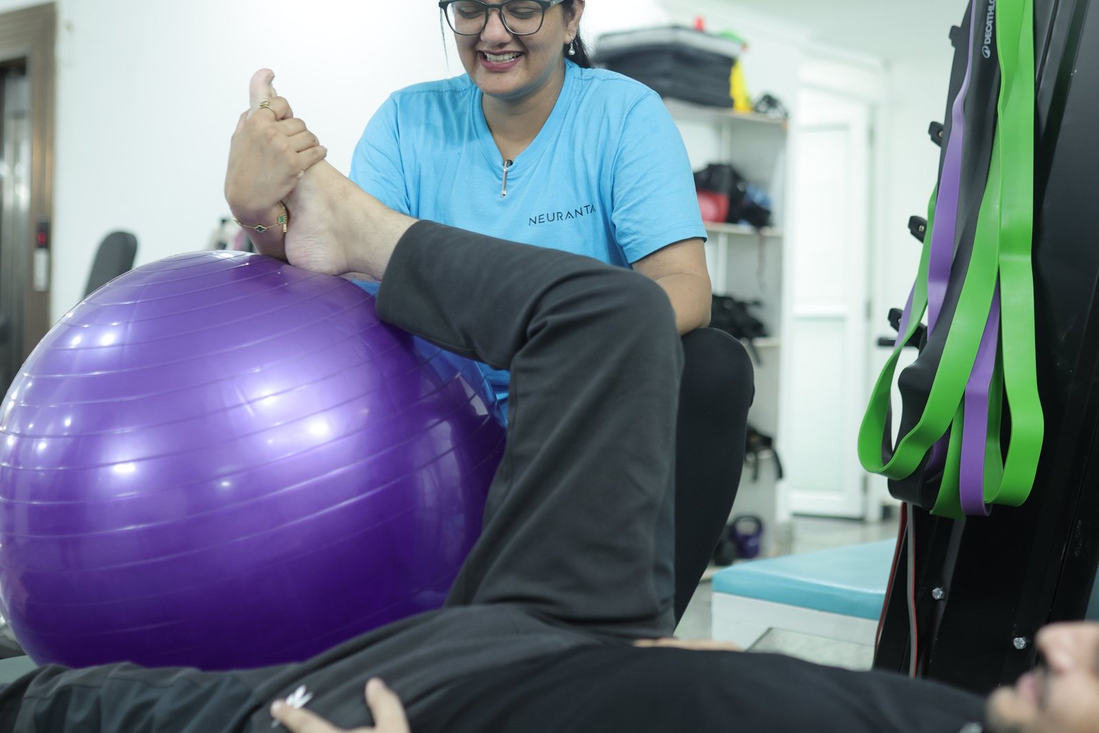 A Neuranta physiotherapist guiding a supported leg exercise over a therapy ball with a patient lying on a mat at the Sector 39 Gurugram centre
